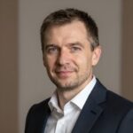 Портрет уверенного российского бизнесмена с дружелюбным взглядом на размытом нейтральном фоне в студии